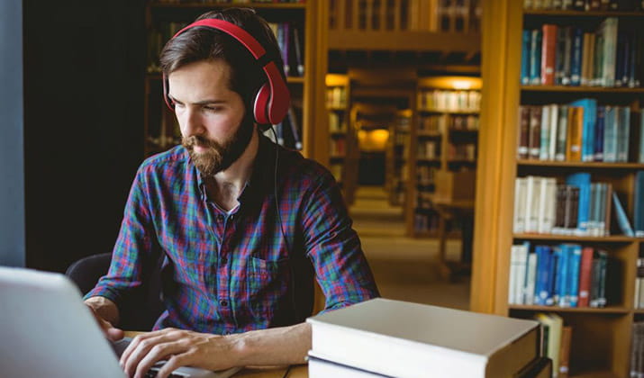 male-concentrating-studying-in-the-library